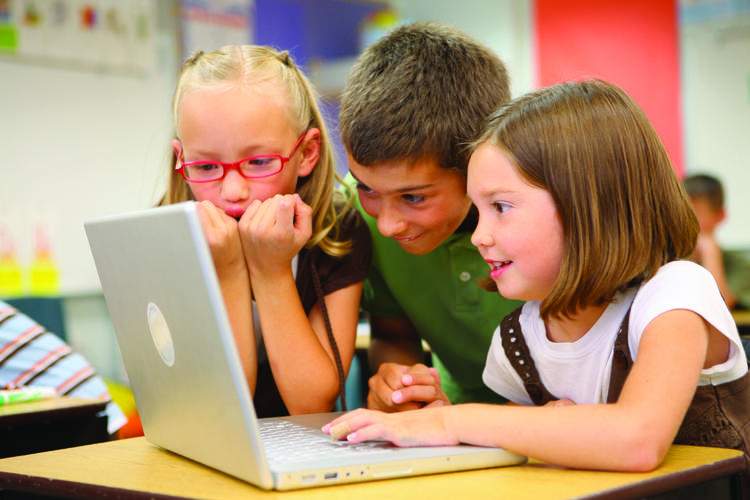 Children engaged and focused at a laptop