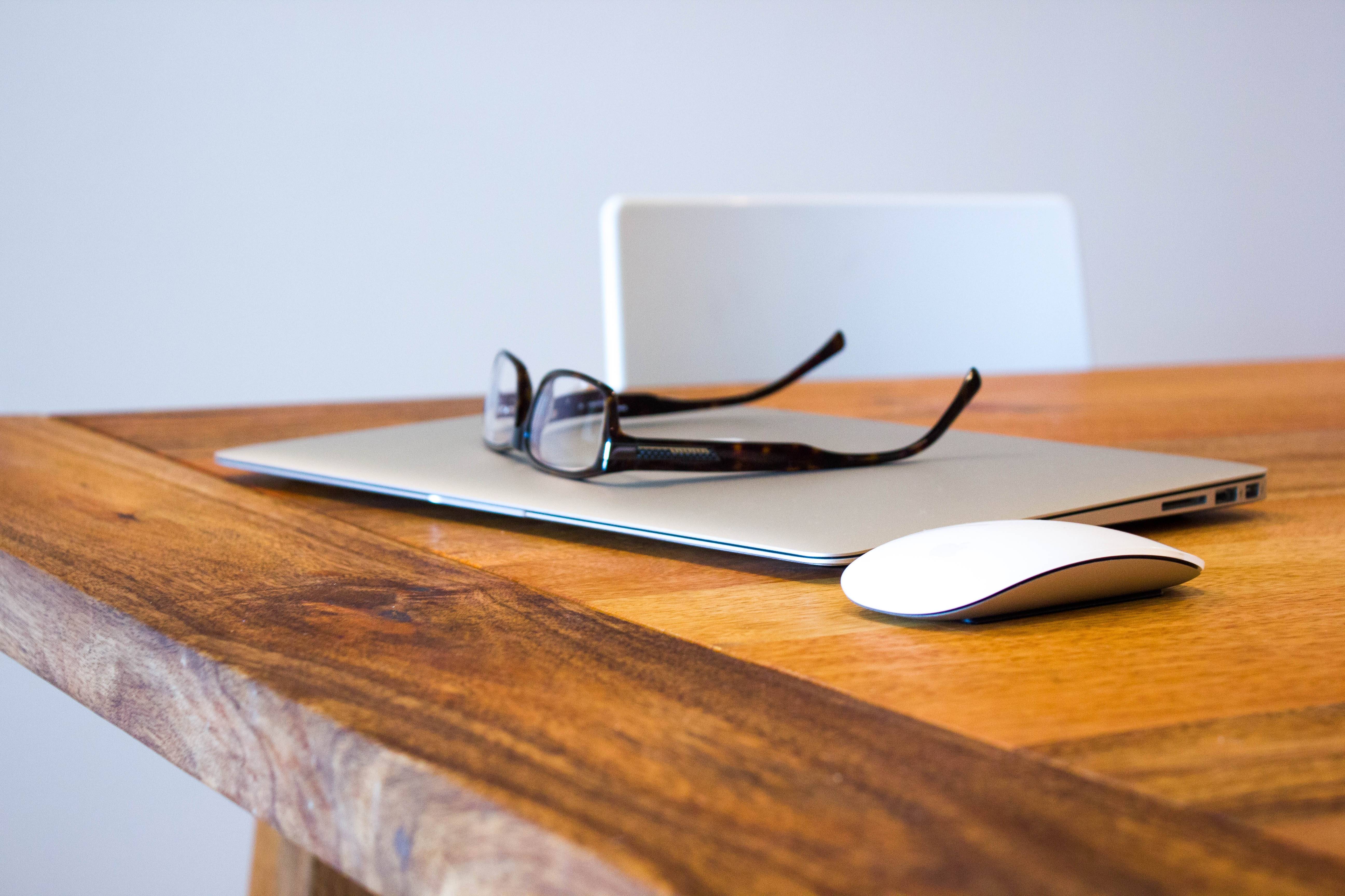 Laptop and glasses on a wooden desk